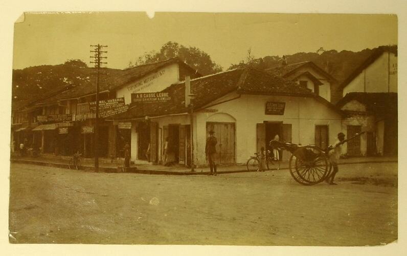 Street scene in Kandy, man pulling small cart in the foreground.