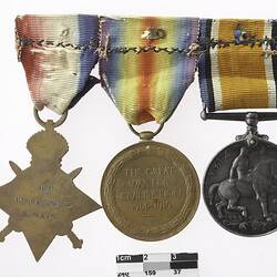 Group of three medals mounted together, with multicoloured ribbons attached to top of medals.