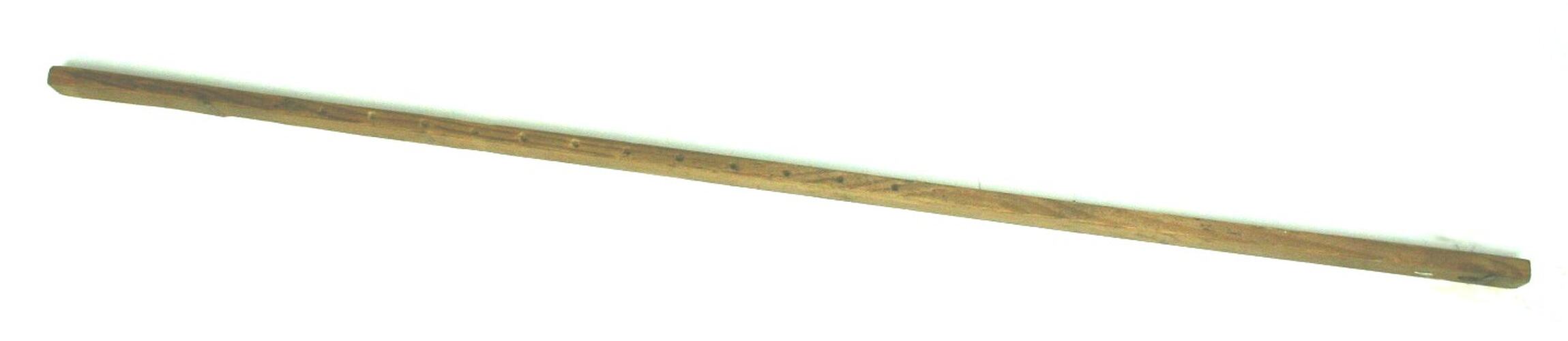 Handcrafted wooden stick with small holes.