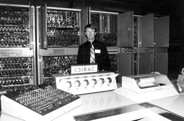 Man posed with computer cabinets and circuit boards.