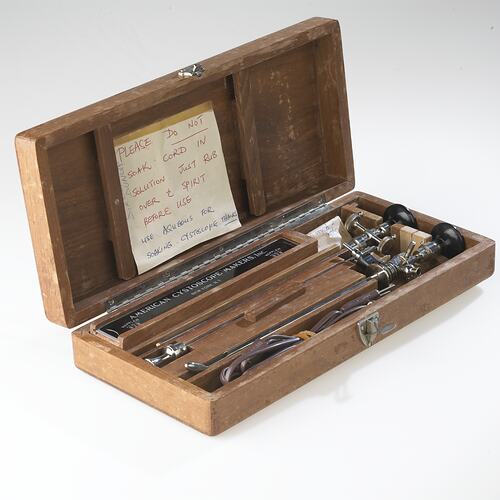 Medical equipment in a wooden box with handwritten instruction.