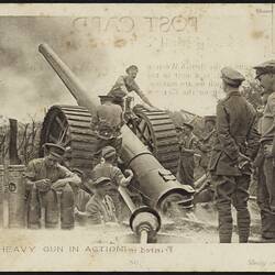 Large gun with soldiers operating. One stands on top of it, others near by.
