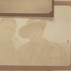 Two servicemen, one wearing hat and smoking cigarette.