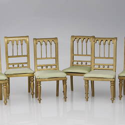 Six wooden upright chairs.