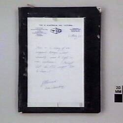 Book with typed and handwritten text, on white cover, with black border.