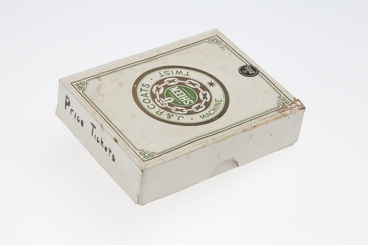 White card box with lid. Central circular logo with text in gold and green ink.