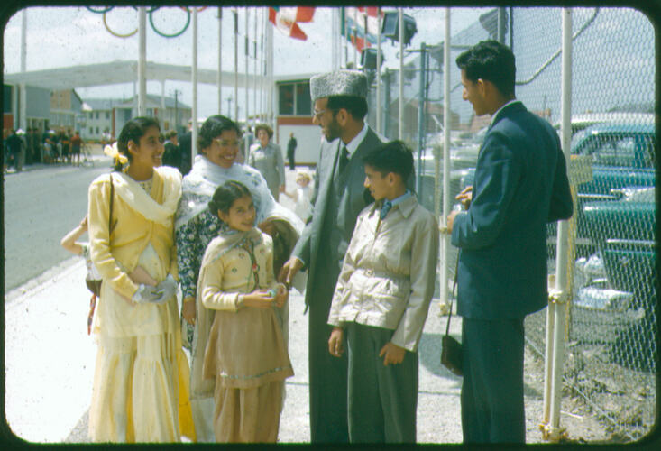 Family group standing next to rows of flags