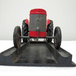 Model tractor with red body and black wheels.