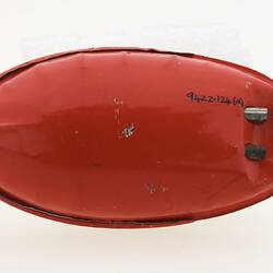 Red underside of little metal speedboat toy.