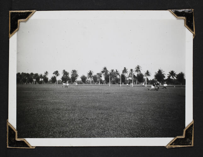 Men playing football game with palm trees in background.