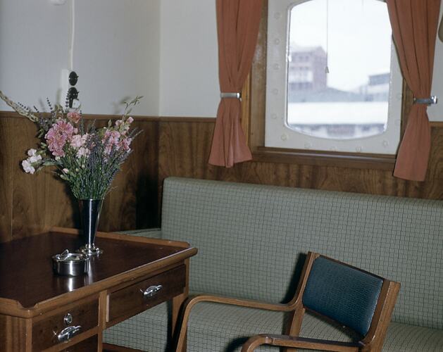 Ship's cabin with table, chair and flowers.