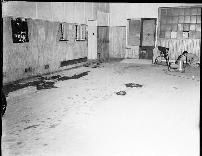 Monochrome photograph two men laying flooring.