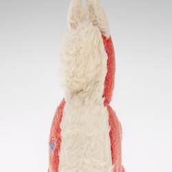 Rear view of red plush toy squirrel with upright white tail.