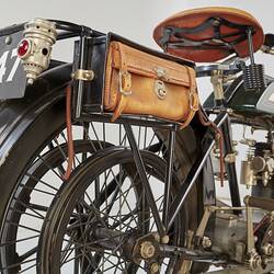 Motor cycle, rear right view. Number plate and leather side satchel.