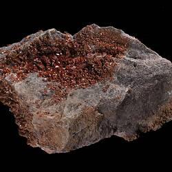 Red-orange crystals on grey rock.