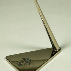 Metal stand with upright angled support and lettering on base.