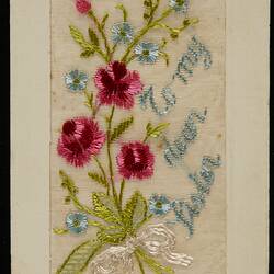 Embroidered posy of red and blue flowers bound with white ribbon set in postcard. Pale blue embroidered text.