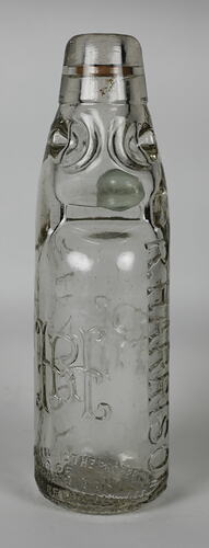 Clear glass bottle with raised inscription.