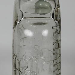 Clear glass bottle with raised inscription.