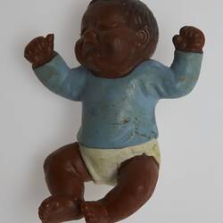 Baby doll wearing a blue top and white pants. The doll has dark brown skin and hair.
