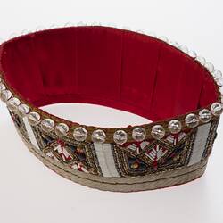 Red fabric crown decorated with clear beads and trimming. Inside lined with red fabric.