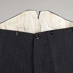 Details of raised waistband on back of black and white woollen trousers.