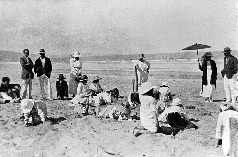 Children digging in sand at a beach.