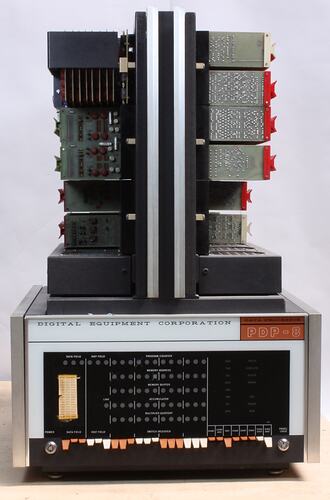 Grey, black rectangular computer. Horizontally stacked circuit boards. Black switches at base.