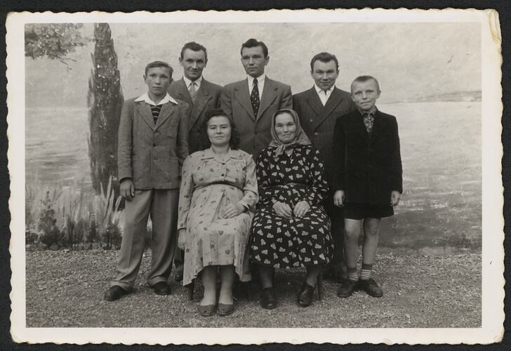Family of seven group portrait. Seascape scene behind them.