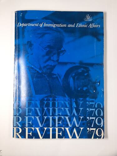 Front cover of book. Blue card cover with white and blue text over image of older man wearing glasses and apron.