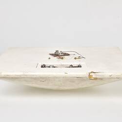 Scuffed white plastic square plate with curved base and rounded corners. Profile.