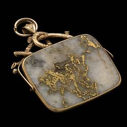 Rectangular pendant featuring white gold-bearing quartz in a gold setting, complimented by a delicate branch-like motif at the top.