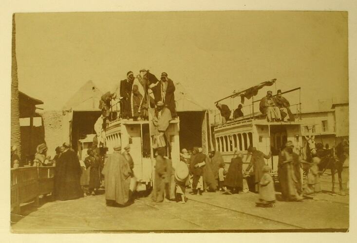 Arab men standing around and on top of tram cars.