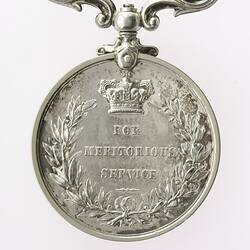 Silver coloured medal With crown in top-centre, text below, surrounded by wreath.