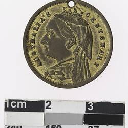 Round gold coloured medal with profile of crowned woman and text surrounding.