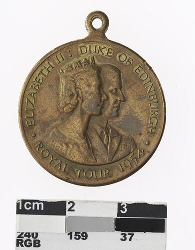 Round bronze medal with profile of man and crowned woman, text surrounding.