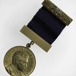 Round gilt medal with 2  bars and purple ribbon. Profile of man, text around.