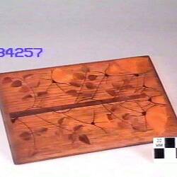 Wooden plaque with pattern of leaves.