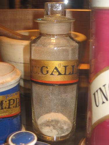 Glass jar with white powder residue. Gold label with black text.
