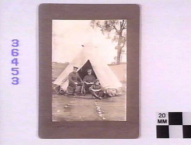 Three men in uniform outside bell tent.