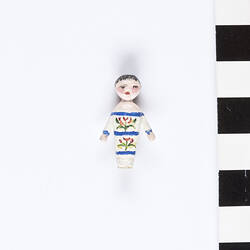 Tiny, painted, wooden doll.