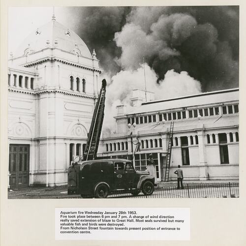Smoke billowing from an ornate domed building that is on fire. Fire truck in front.