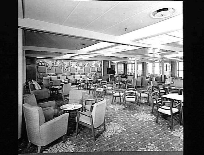 Ship interior. Room with upholstered chairs and armchairs around tables. Lounge area.