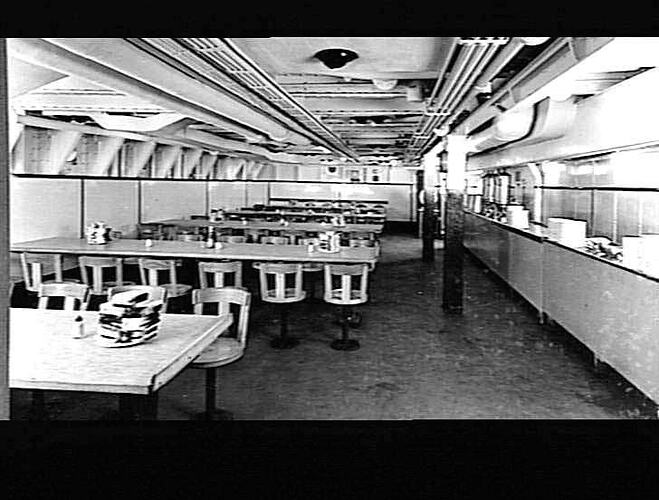 Ship interior. Crew's dining area with fixed tables and chairs.