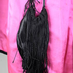 Detail of black tasselled decoration, vibrant pink lining.