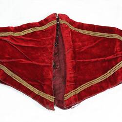 Back of child's wide scalloped edged red velvet belt (folded) with gold cord detail.