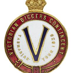 Crowned round enamel badge with "V" on white background with gold text and red border.
