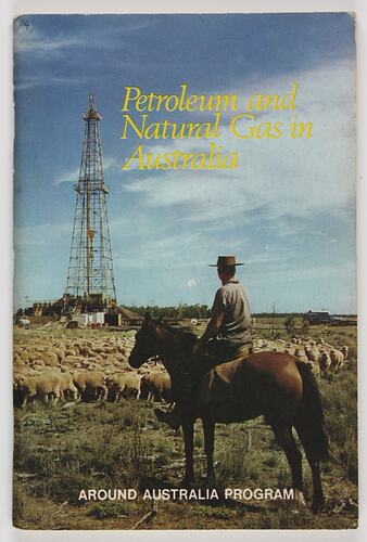 Man on horseback looking over sheep and mineshaft.