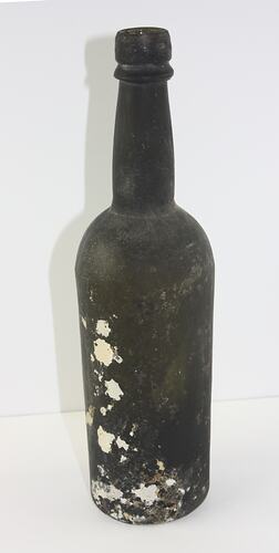 Glass bottle, painted black with blobs of white chemical spilled down the side.