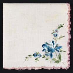 Folded handkerchief with blue flowers embroidered at corners.